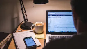 Blogger analyzing easy ranking keywords on laptop with coffee and notes