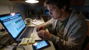 Tired blogger tuning SEO, speed, and security settings on a laptop with analytics open