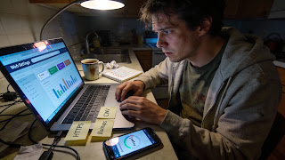 Tired blogger tuning SEO, speed, and security settings on a laptop with analytics open