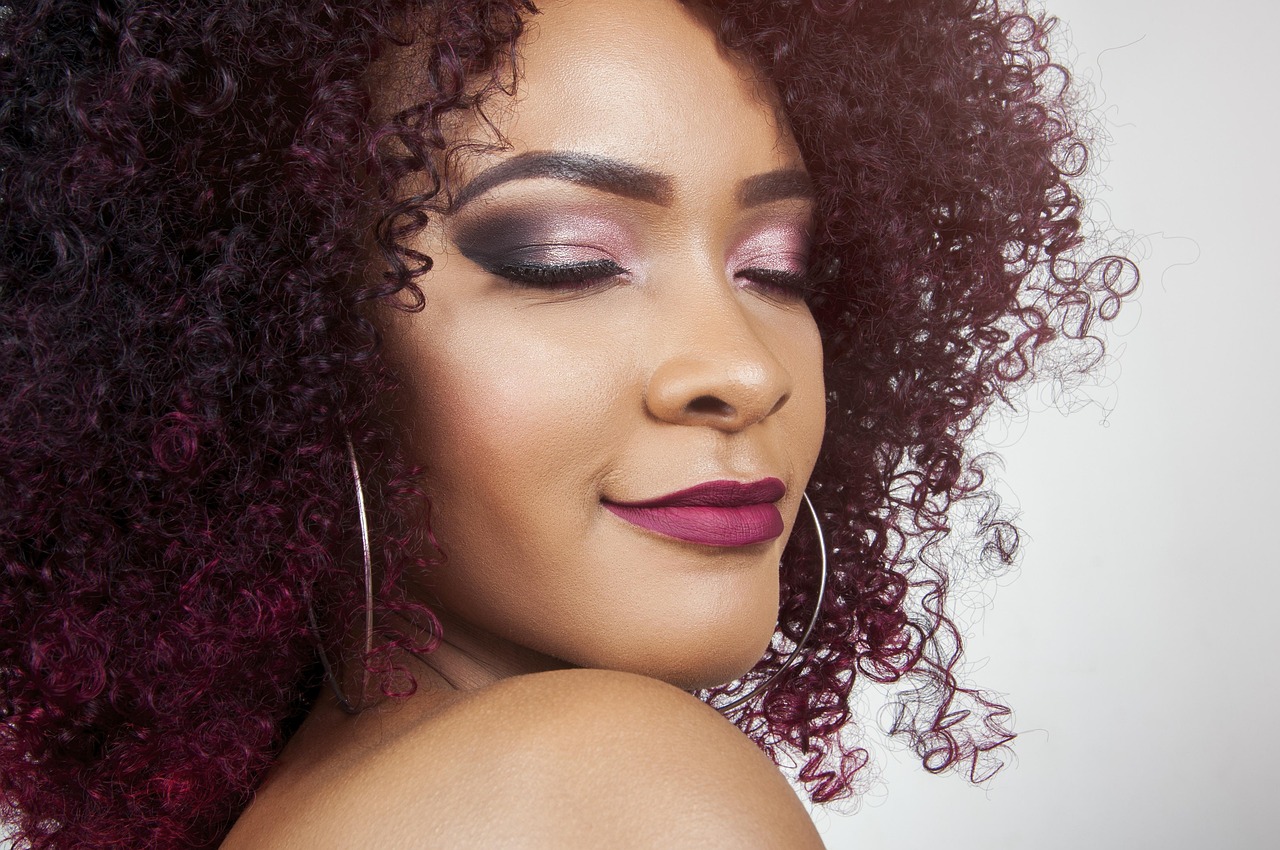 curly hair products - a woman with defined curly hair applying a moisturizing leave-in cream