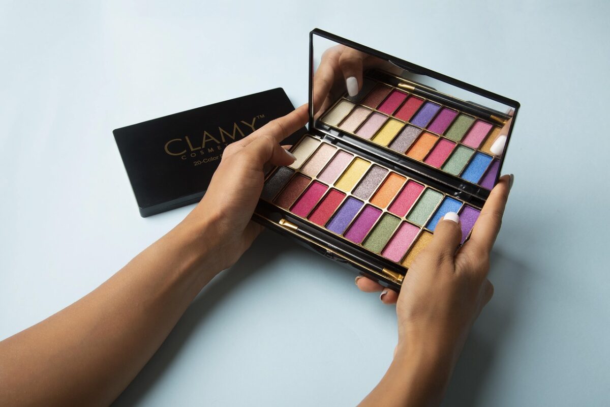 an open eyeshadow palette of neutral shades beside a similar dupe palette on a marble countertop